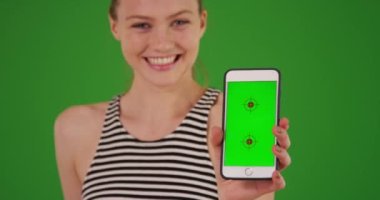 Yeşil ekranda yeşil ekranlı akıllı telefonu tutan mutlu milenyum kızının portresi. Anahtar ya da birleşik olmak üzere yeşil ekranda.