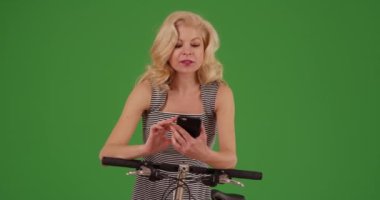 Neşeli beyaz kadın yeşil ekranda yön tarifi için cep telefonu kullanarak bisiklet sürmeye çıkıyor. Anahtar ya da birleşik olmak üzere yeşil ekranda.