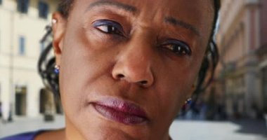 Uzaktan bakan olgun siyahi kadına yaklaş. Yaşlı Afro-Amerikan kadın portresi, kederli bir şekilde kameradan dışarı bakıyor. 4k