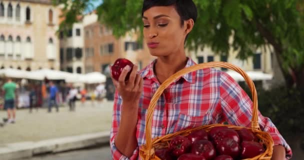 アフリカ系アメリカ人女性がジューシーなリンゴに噛んだ笑顔の肖像 健康的な魅力的な若い黒人女性は イタリアのヴェネツィアで果物を食べる — ストック動画