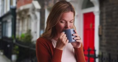 Dışarıda kahve içen kadın portresi. Çekici beyaz kadın gülümsüyor ve kahveden hoşlanıyor. 4k