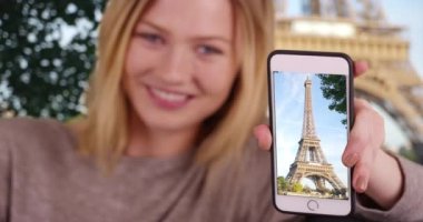 Güzel beyaz kız Eyfel Kulesi 'nin cep telefonu fotoğrafını tutuyor. Paris 'te tatil fotoğraflarını paylaşan bin yıllık bir kadının portresi. 4k