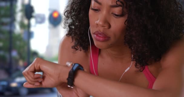 忙しい通りで時計を使用してかなり黒い女性のジョギングの閉鎖 アフリカ系アメリカ人女性が逃走中の接近 — ストック動画
