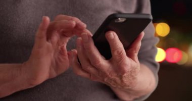 Yetişkin bir kadının telefon kullanarak Bokeh arka planındaki mesajları okuduğu yakın plan. Yaşlı birinin cep telefonuyla dışarıda mesajlaşırken çekilmiş sıkı bir fotoğrafı. 4k