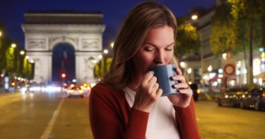 Geceleri kahve içen Paris 'li kadının yakın portresi. Çekici beyaz bir kadın akşamları kahve içiyor. 4k