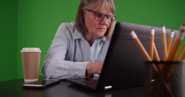 Yeşil kromakey kompozit ekranda dizüstü bilgisayar kullanan mutlu yaşlı kadın. Evde taşınabilir bilgisayar kullanan yaşlı bir kadının portresi. 4k