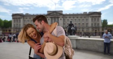 Buckingham Sarayı 'nın dışında sevgili genç bir çiftin portresi. Mutlu ve romantik erkek ve kadın turistler Londra 'da eğleniyor. 4k