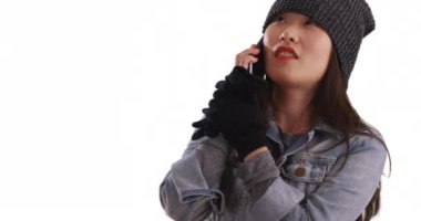 Neşeli bin yıllık kadın cep telefonuyla konuşuyor ve beyazı sıcak tutmaya çalışıyor. Mutlu Asyalı genç bir kadın soğuk havada telif uzayı geçmişinde akıllı telefondan sohbet ediyor. 4k