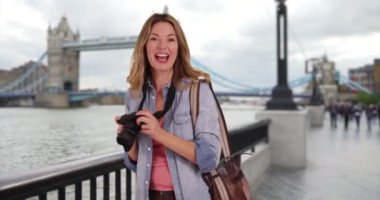Kule Köprüsü 'nün fotoğraflarını çeken seyahat fotoğrafçısı. Londra 'da kamerasıyla gülümseyen kadın turist portresi. 4k