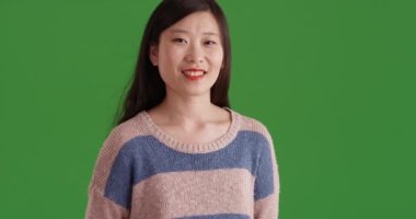 Yeşil krom anahtar kompozit duvarında gülümseyen mutlu Asyalı kadın. Genç kız öğrenci yeşil ekranda izole edilmiş görünüyor. 4k