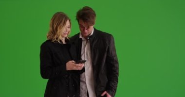 Çekici bir kadın, erkek arkadaşıyla birlikte yeşil ekranda cep telefonundan mesaj atıyor. Anahtar ya da birleşik olmak üzere yeşil üzerine.
