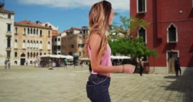 Venedik caddesinde müzik dinleyen ve dans eden mutlu çekici kadın. Dışarıda akıllı telefonla müzik dinleyen kaygısız bir kadın. 4k