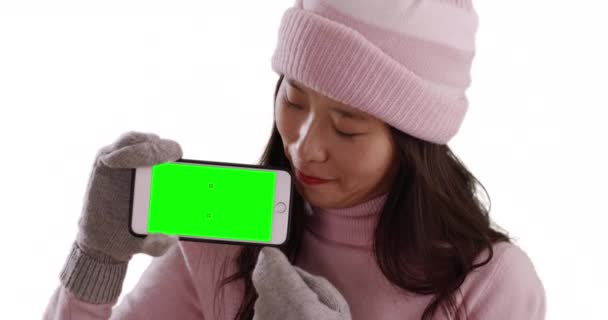 Lächelnde Asiatin Winterkleidung Mit Smartphone Und Grünem Bildschirm Auf Weißem — Stockvideo