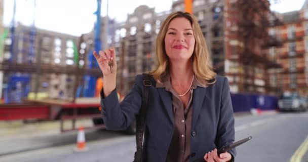 현장에 전문직 여성의 미소짓는 부동산 중개업자는 건설중인 아파트 건물의 열쇠를 — 비디오