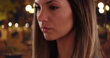 Güzel esmerin yakın plan portresi. Gece vakti dışarıda derin düşüncelere dalmış. Yirmili yaşlarda parlak bir gecede dalgın dalgın duran bir kızın yakın çekimi. 4k