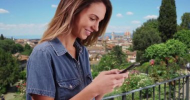 Floransa 'da gülümseyen ve cep telefonuyla mesajlaşan beyaz bir kadın. 20 'li yaşlarda, eve dönen arkadaşlarına mesaj atan bir kadın. 4k