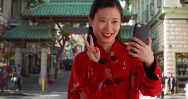 微笑的千禧年女人用智能手机在中国城门口自拍 在旧金山 年轻的亚洲女人穿着传统的中国服装 — 图库视频影像