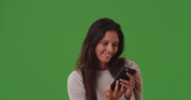 Yeşil ekranda cep telefonu kamerasıyla selfie çeken hoş beyaz bir kadın. Mutlu çekici kadın yeşil ekranda özçekim görüntülerini yakalamak için akıllı telefon kullanıyor. 4k