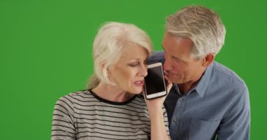 Üst düzey çift evde yeşil ekranda akıllı telefondan konuşuyor. Anahtar ya da birleşik olmak üzere yeşil ekranda.