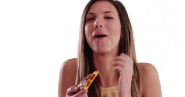 千年紀の少女が近くで笑って白いコピースペースでピザを食べています 白地にピザのスライスを楽しむ茶色の髪の魅力的な女性 — ストック動画