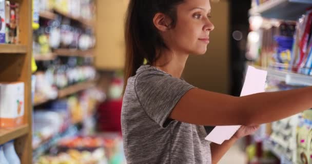 Közelkép Női Vásárló Élelmiszerbolt Böngésző Polc Tétel Fiatal Olvas Bevásárlólistáról — Stock videók