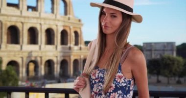 Roman Colosseum tarafından poz verilen yaz kıyafetli çekici bir kadın portresi. Roma, İtalya 'da fötr şapka takmış şık, çekici bir kadın. 4k