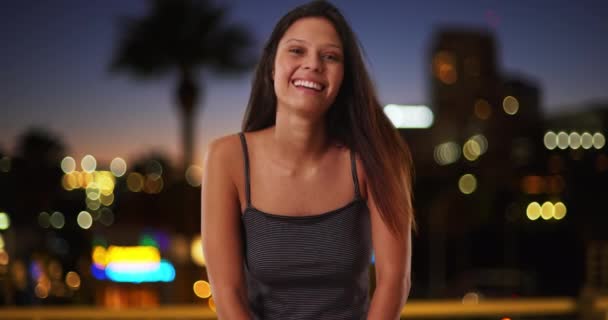 美丽的白人女孩在城市的夜晚 笑着看着相机 一个穿着条纹背心的20多岁的风趣女人 — 图库视频影像