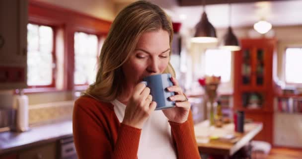 現代的なキッチンのマグカップからコーヒーや紅茶を飲む白人女性のクローズアップ カメラで笑顔 昼間は屋内でホットドリンクを楽しむ魅力的な白い女性の肖像画 — ストック動画