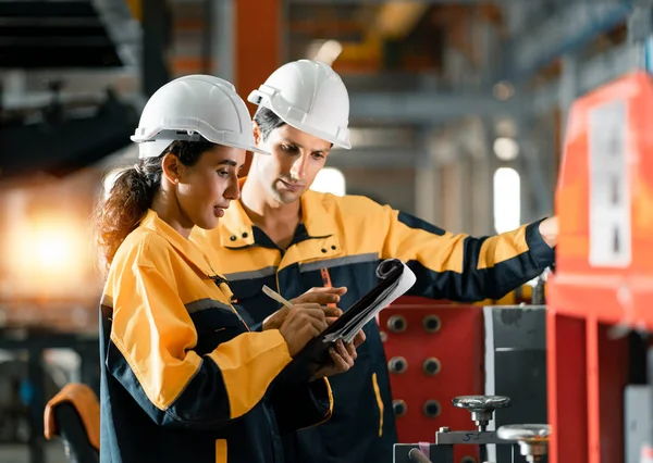 İki profesyonel mühendis, işçi ve teknisyen iş hakkında konuşur çelik metal fabrikası fabrikasında yürür. Siyahi Afrikalı erkek ve kadın sıkı şapka kalite makine takıyor