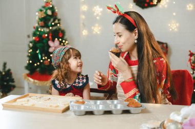 Mutlu komik aile anne ve çocukları Noel kurabiyesi pişirir. Çocuklar ve aileler Noel için kurabiye hazırlıyor. Noel kurabiyesi hamuru yapmak için evde oturmuş Noel süveteri giyen tatlı çocuklu bir anne..