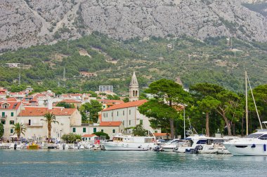 Makarska, Hırvatistan - 4 Ağustos: Hırvatistan 'ın Makarska kentinde 4 Ağustos 2020 tarihinde Adriyatik Denizi kıyısındaki bir tatil beldesinde dağların arka planına karşı liman