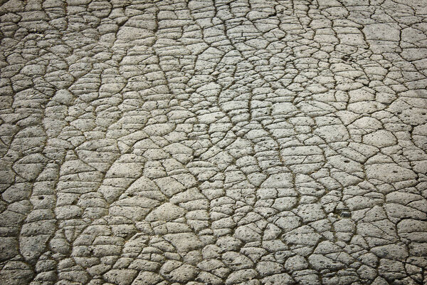 серый фон с потрескавшейся старой дорогой. Текстура треснувшего асфальта крупным планом.