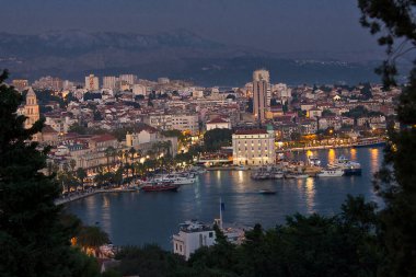 Hırvatistan 'ın Split kentinin en iyi manzarası. Akşam şehir manzarası, arka planda sokak ışıkları ve dağlar..  