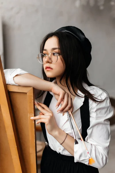 筆を手にした作業中の白いシャツを着た若い女性の肖像画です — ストック写真
