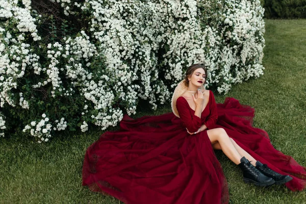 穿着红色衣服的漂亮姑娘坐在荆棘边 开着白花 — 图库照片