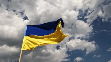 Ukrayna bayrağı bulutlu bir gökyüzüne karşı rüzgarda dalgalanıyor..