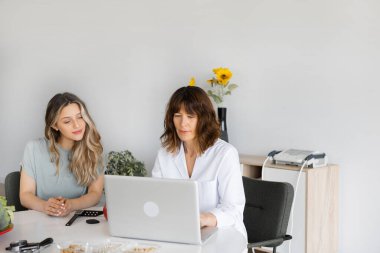 Diyet danışmanlığı yaparken, içeride, ofiste genç bir bayan hastayla konuşurken not defterine yazan ve onunla konuşan yetişkin bir beslenme uzmanı. Boşluğu kopyala