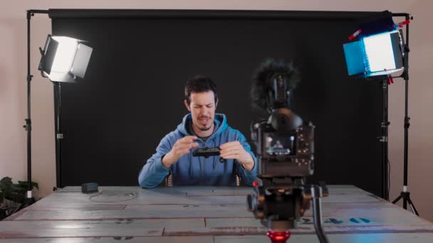 Young Caucasian Man Sitting Table Photography Studio Recording Video Camera — стоковое видео