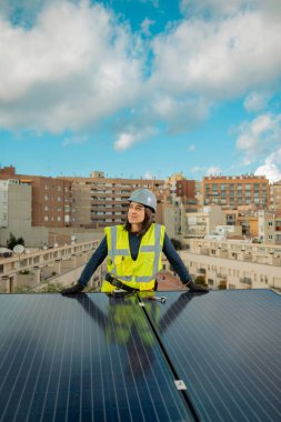 Kafkasyalı kadın elektrikçi portresi, sarı yelek, çalışan güneş paneli yenilenebilir enerji, fotovoltaik hücreler, elektrik santrali şehir merkezine elektrik sağlıyor. Dikey