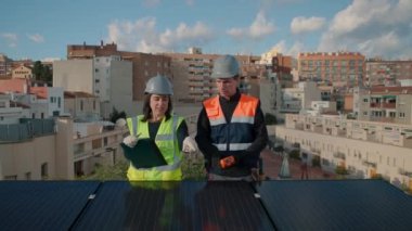 Güneşli bir günde fotovoltaik bir çatıdaki eğim açısı derecesini ölçen teknik mühendisler, güneş panelleri bakım ve teftişinde çalışan kadın ve erkek. Ön görünüm, 4k yatay görüntü