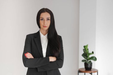 Ofiste durmuş, kollarını kavuşturup kameraya bakan, kendine güvenen, uzun saçlı beyaz bir kadının portresi. Yönetici, iş kadını. Kapalı, Yatay, Boşluğu Kopyala