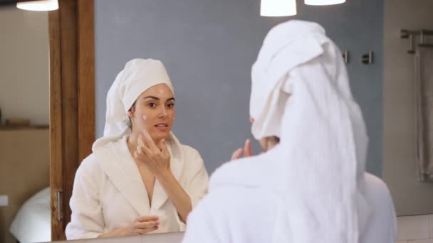 Pretty Young Woman Towel Wrapped Head Bathrobe Applying Cream Skincare — Stock Video