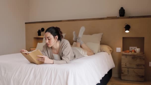 Mujer Morena Soñadora Con Pijama Leyendo Libro Mientras Está Acostada — Vídeo de stock