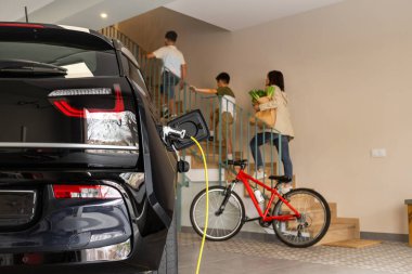 Tanımlanamayan kadın ve çocuklar evdeki merdivenleri çıkarken Elektrik İdaresi 'nde şarj edilecek. Aile Enerji Bilinci, Sürdürülebilir Kaynaklar. Bulanık arkaplan, Yatay