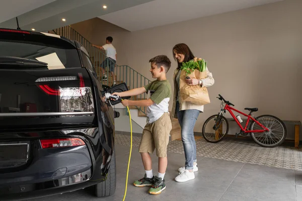 Moeder Zoon Laden Thuis Elektrische Auto Jongen Helpt Vrouw Met — Stockfoto