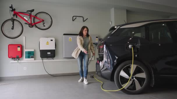 Жінка Паркується Гаражі Підключає Зарядний Пристрій Розетки Електромобіля Відновлювані Будинки — стокове відео