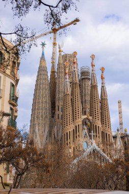 BARCELONA, ESPANA - 13 Şubat 2023. 13 Şubat 2023 'te Barcelona İspanya' da Sagrada Familia Bazilikası 'nın inşaat halindeki binaları ve ağaçlarıyla sokak manzarası.