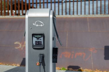Elektrikli araç şarj istasyonunun fişi takılı bir kablosu var. Temiz enerji ve kentsel hareketlilik kavramı. Yatay kopyalama uzayı