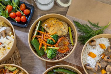 Izgara tavuk, sebze, kinoa, makarna ve pirinçle servis edilen çeşitli yemek kaselerinin genel manzarası. Taze bitkiler, domatesler ve cam kavanoz detay ekler. Renkli yemek tasarımı. Yatay, kopyalama uzayı.