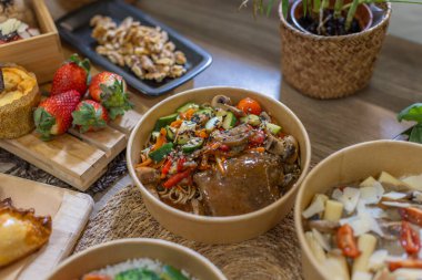 Cilalı biftek, erişte, mantar, kabak ve kırsal bir masada biber içeren canlı bir paket servis kasesine yakın plan. Taze malzemelerle çevrili. Yatay görüntü, üst görünüm.